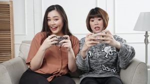 two womans playing mobile games on a sofa